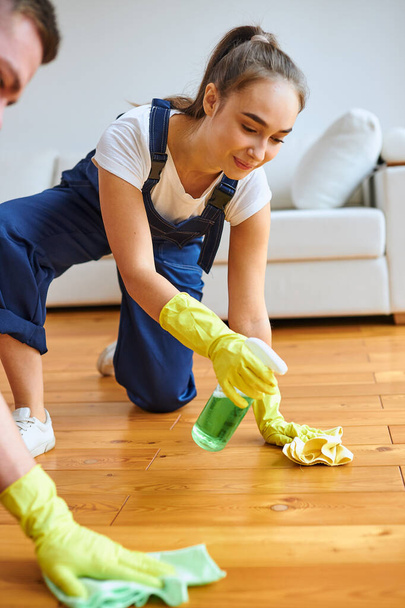 Positive female cleaner polishing floor with rag and spray - Foto, Imagem