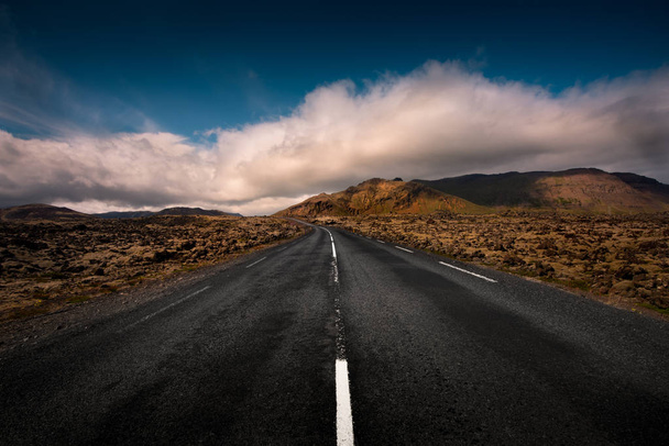 Un camino islandés vacío conduce a través de una cordillera
 - Foto, Imagen