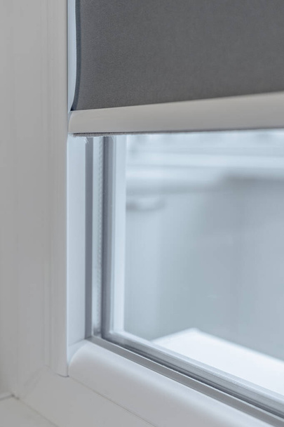 Egy műanyag ablak szilánkja. Pvc ablak leeresztett rolós redőnyökkel - Fotó, kép