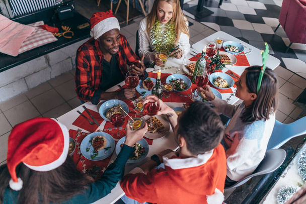 Ludzie siedzący przy świątecznym stole i świętujący Nowy Rok lub Boże Narodzenie - Zdjęcie, obraz