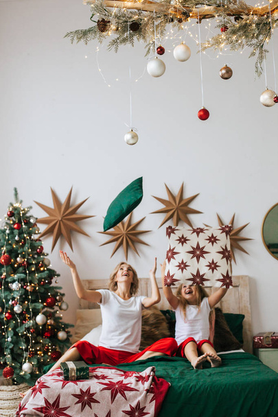 Portrait of mom and daughter in Christmas evening have fun in bed - Foto, Imagen