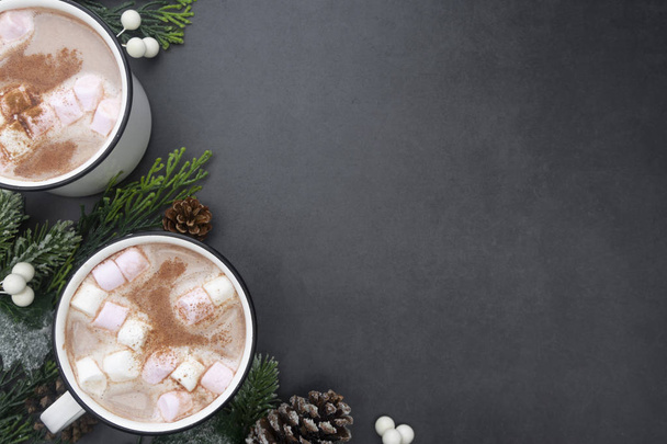 Hot chocolate mugs with marshmallows. Flat lay with fir branches. Gray background. Warm winter drink. - Фото, изображение