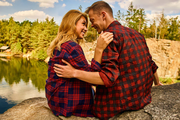 Couple of tourists exploring a new places. Handsome couple on nature near the lake at forest background. - Photo, image