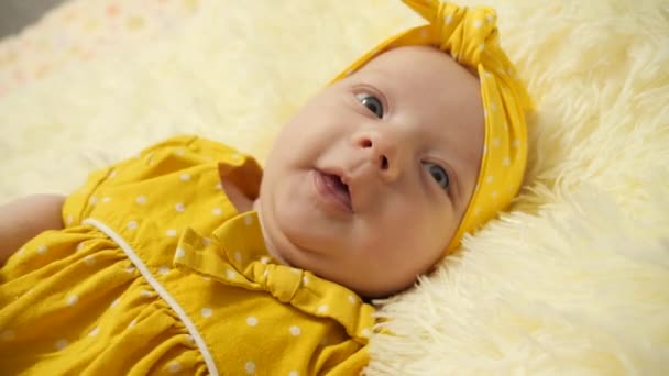Portrait. Bébé dans une robe jaune et un pansement jaune sur la tête, s'amusant à sourire et à gesticuler
. - Séquence, vidéo
