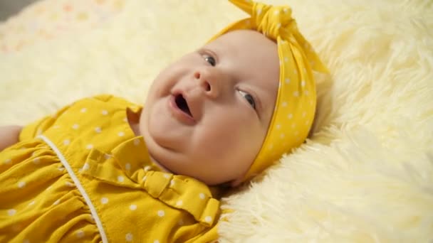 Portre. Sarı elbiseli bebek ve kafasında sarı bandaj, hapşırıyor.. - Video, Çekim