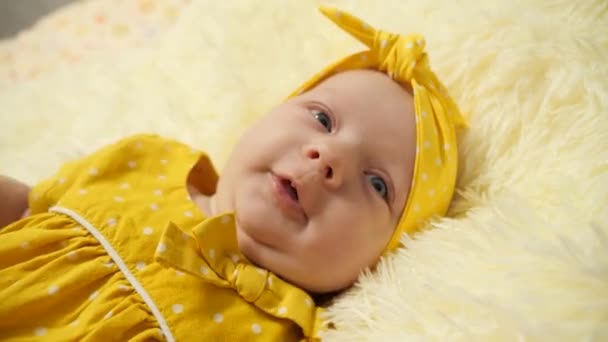 Porträt. Baby in gelbem Kleid und gelbem Verband am Kopf gähnt - Filmmaterial, Video
