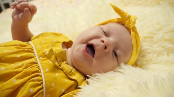 Menina em um vestido de bolinhas amarelas e uma bandagem amarela ativamente gestos, sorrisos, e mostra sua língua
 - Filmagem, Vídeo