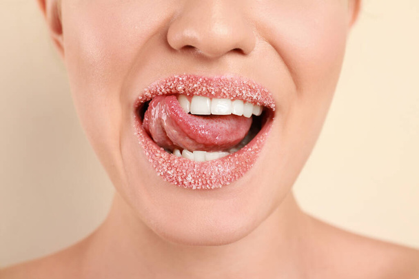 Mujer joven con labios de azúcar sobre fondo beige, primer plano
 - Foto, Imagen