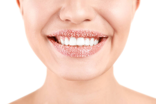Young woman with sugar scrub on lips against white background, closeup - Foto, afbeelding