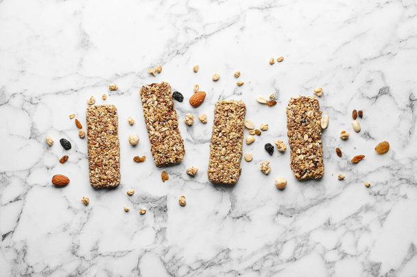 Healthy granola bars on white marble table, flat lay - Foto, imagen