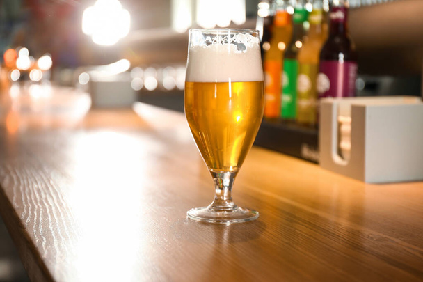 Glass of beer on wooden table in pub - Fotoğraf, Görsel