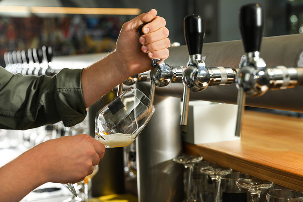 Bartender pouring fresh beer into glass in pub, closeup - Fotografie, Obrázek