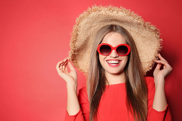 Young woman wearing stylish sunglasses and hat on red background. Space for text - Zdjęcie, obraz