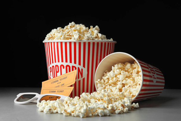 Popcorn, cinema tickets and 3d glasses on grey table - Фото, изображение