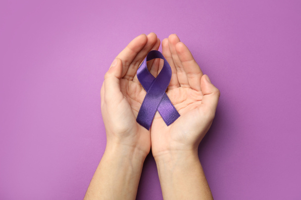 Woman holding purple ribbon on lilac background, top view. Domestic violence awareness - Foto, Imagen