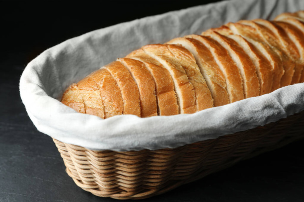 Slices of bread in basket on black table, closeup - Foto, afbeelding