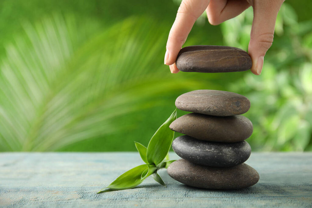 Woman stacking stones on table against blurred background, closeup. Zen concept - Photo, Image