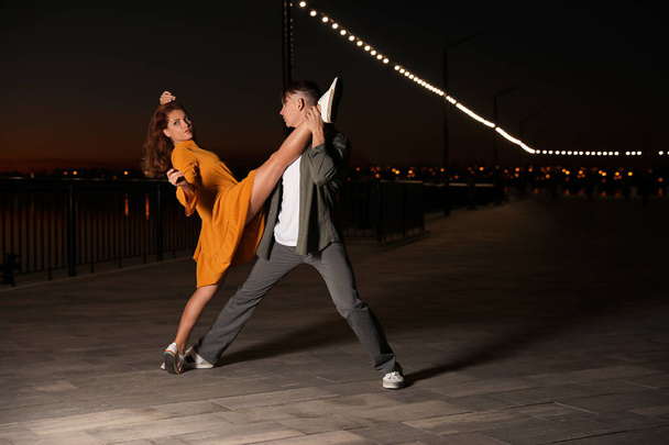 Beautiful young couple practicing dance moves in evening outdoors - Foto, imagen