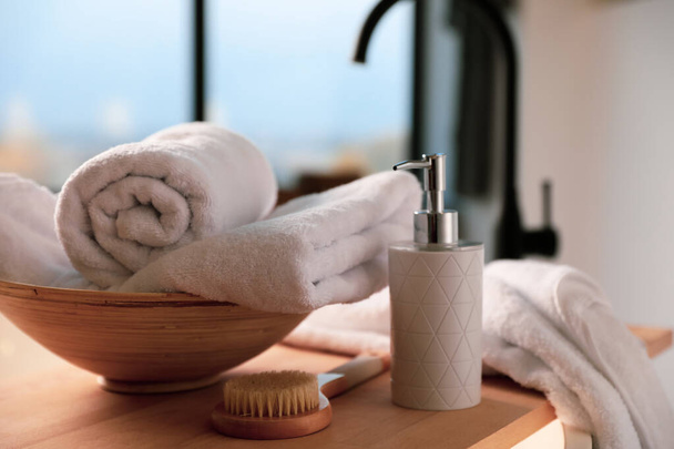 Serviettes propres, distributeur de savon et brosse de douche dans la salle de bain
 - Photo, image