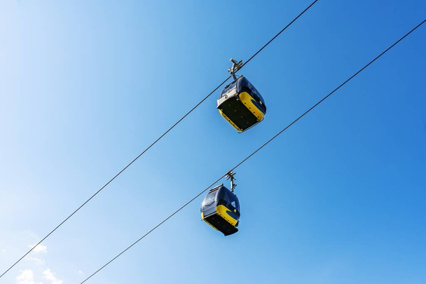 Cabines de téléphérique s'élevant sur la montagne contre le ciel bleu
. - Photo, image
