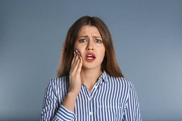 Woman suffering from toothache on grey background - Foto, Bild