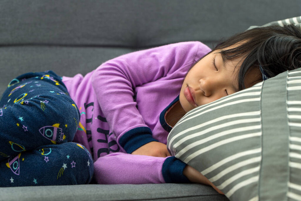 Little Asian child taking nap on couch - Fotó, kép