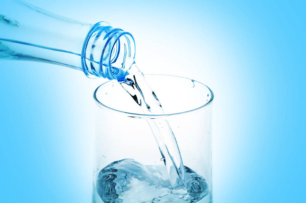 Wasser aus Flasche in Glas auf blauem Hintergrund gießen - Foto, Bild