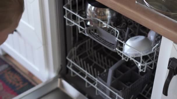 女性が食器洗い機を開き汚れた皿を置きます - 映像、動画