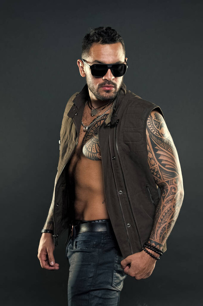 Bearded man with tattoo on chest and arms. Tattoo model with beard on unshaven face. Tattooed man with six pack and ab. Fashion style and trend. Fashion macho in trendy sunglasses - Foto, Imagem