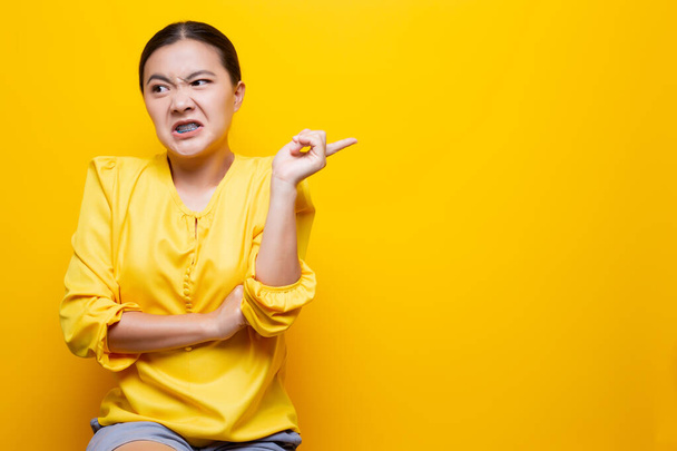 Woman show disgust gesture isolated over yellow background - Photo, image