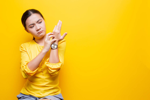 Mujer rascándose las manos aislada sobre fondo amarillo
 - Foto, imagen