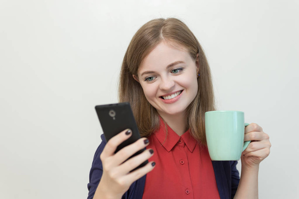 Souriant jeune femme caucasienne fille textos ou jouer au jeu sur téléphone mobile
 - Photo, image