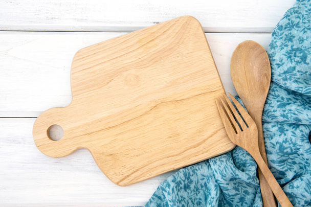  a chopping board and tablecloth with wooden fork and spoon on w - Valokuva, kuva