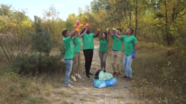 Szczęśliwi zróżnicowani aktywiści przybijają piątkę po zbiórce śmieci - Materiał filmowy, wideo