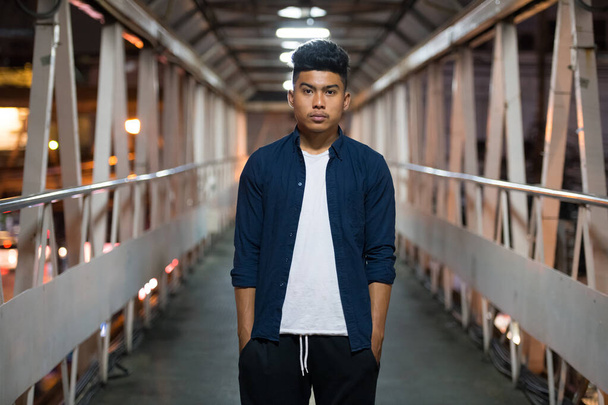 Young Asian man standing on the footbridge at night - Foto, immagini