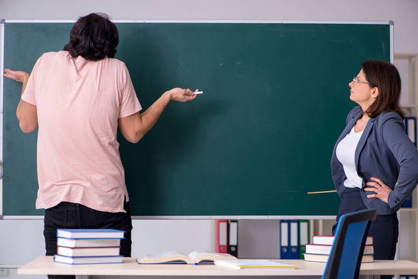 Old female teacher and male student in the classroom - Photo, Image