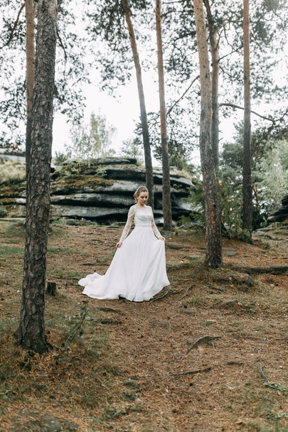 Elegant ceremony in European style. Beautiful bride in white flying dress in the forest.  - Foto, imagen