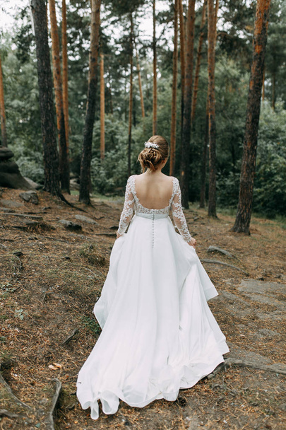 Elegant ceremony in European style. Beautiful bride in white flying dress in the forest.  - 写真・画像