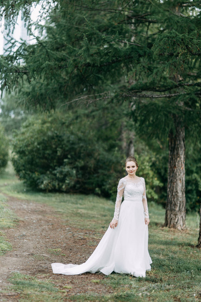 Elegant ceremony in European style. Beautiful bride in white flying dress in the forest.  - Фото, зображення