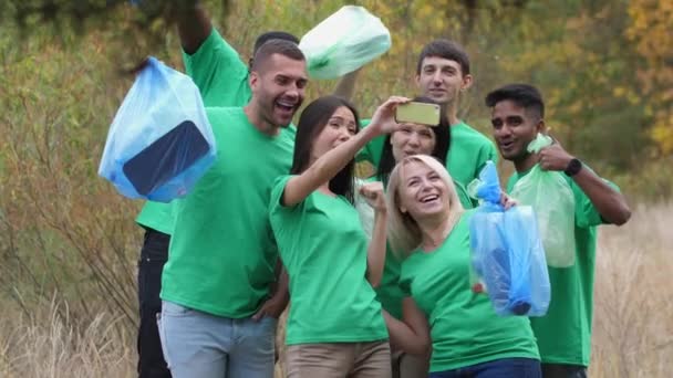 Glimlachende diverse vrijwilligers nemen selfie in het bos - Video