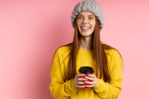 Redhead woman holding disposable cup of coffee - Foto, afbeelding