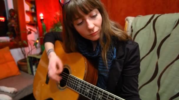 Dívka hraje na kytaru v obývacím pokoji. - Záběry, video