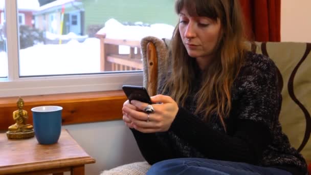 Girl using mobile phone in a living room - Footage, Video