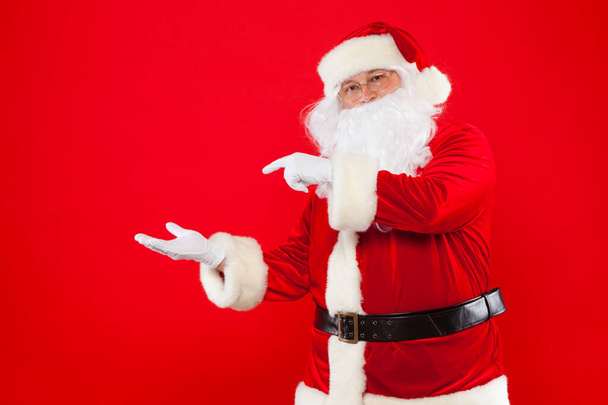 Santa Claus pointing in blank a place, red background - Photo, image