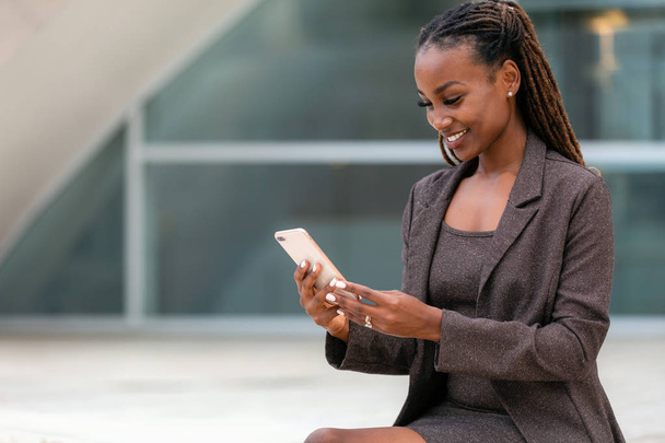 Όμορφη αφρικανή επιχειρηματίας στο γραφείο χρησιμοποιώντας την τεχνολογία smartphone, 5g, 4g, Lte, ευρυζωνικό διαδίκτυο - Φωτογραφία, εικόνα