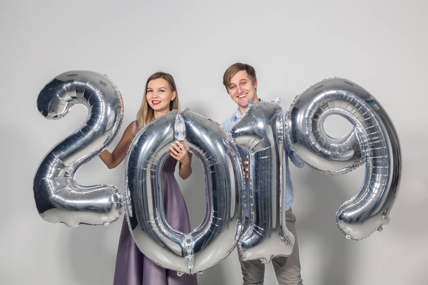 Nouvel an, concept de fête et de vacances - couple amoureux s'amuser avec signe 2019 fait de ballons en argent pour la nouvelle année
 - Photo, image