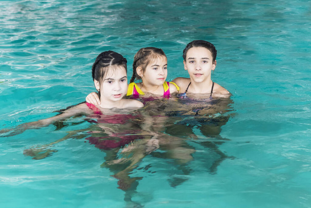 3 人の女の子がプールで泳ぐ。プールの姉。三幸せな女の子は、プールで遊ぶ。水の美しい女の子いて、泳ぐ楽しみ。アクティブな休日. - 写真・画像