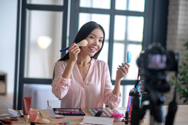 Blogger holding brush while filming makeup tutorial - Zdjęcie, obraz