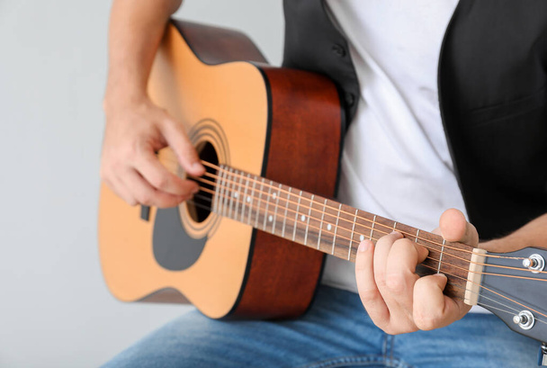 Man playing guitar on light background, closeup - Φωτογραφία, εικόνα