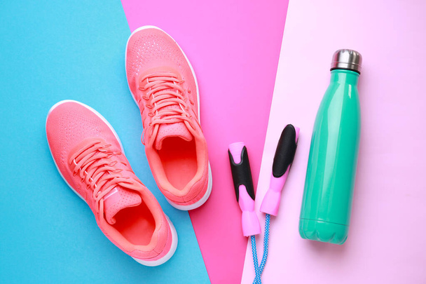 Sports water bottle, shoes and jumping rope on color background - Photo, Image
